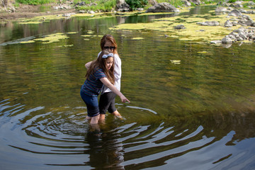 Woman and daughter crossing carefully in a stream or river