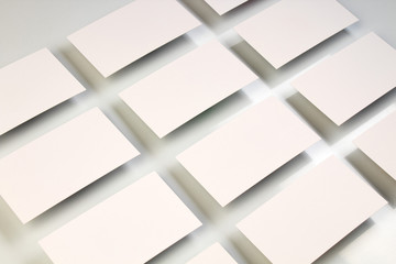 Mockup of horizontal business cards stacks arranged in rows at white textured paper background.