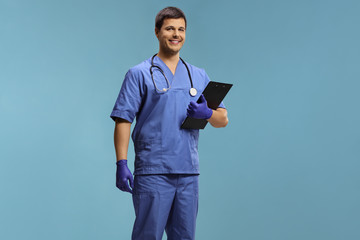 Young male doctor in a uniform wearing gloves and holding a clipboard