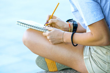 girl draws in a notebook sitting on the pavement