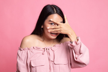 Beautiful young Asian woman peeking through fingers.