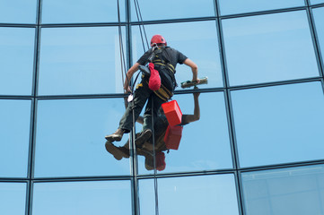 portrait of worker washing windows of the modern building.