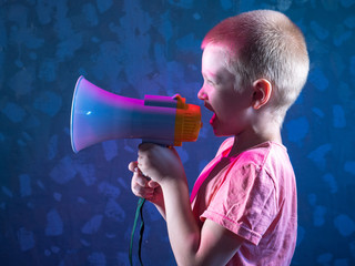 Child screaming into loudspeaker..Kid shouting through megaphone. Communication concept. Black background as copy space for your text