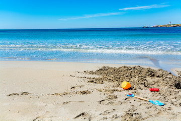 Fototapeta na wymiar Crystal clear blue Mediterranean sea water on St.Croix Martigues beach and kids beach toys, Provence, France