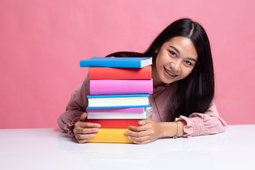 Happy young Asian woman read a book with books on table.