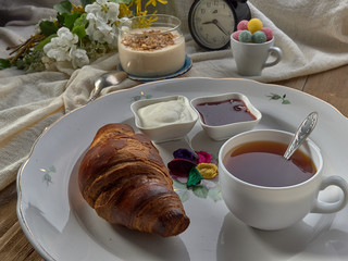 Croissant,jam ,tea with lemon, on a porcelain dish