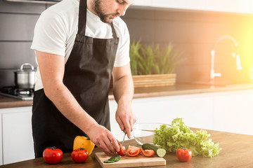 Young trendy man cooking healthy food in the morning