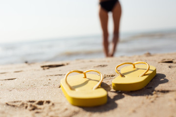 Flip Flop shoes on sandy beach and woman body