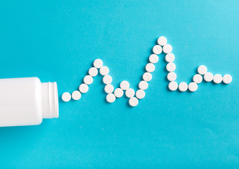 medicine, healthcare and pharmacy concept - pills and of drugs in shape of the heart and heart rhythms