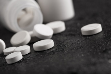 Assorted pharmaceutical medicine pills, tablets and capsules. Black background.