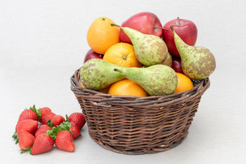 Fresas junto a una cesta con frutas variadas