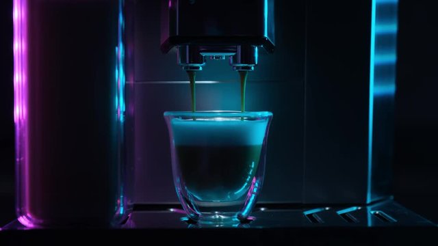 Coffee machine makes coffee with milk. Coffee machine with a cup of hot cappuccino coffee. Maker with cup of  coffee with milk. Real time footage. Art concept. Fluorescent colors.