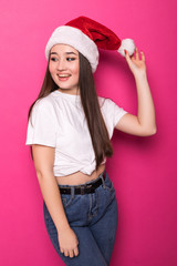 Santa christmas asian woman smiling portrait. Beautiful young woman in red wearing santa hat isolated on pink background.