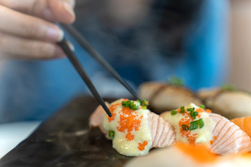 Eating Sushi with chopsticks. Fresh sushi japanese food in restaurant.