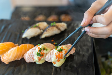 Eating Sushi with chopsticks. Fresh sushi japanese food in restaurant.