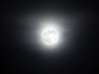 Foggy sky with the bright full moon glowing in the dark