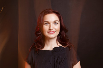 Fototapeta premium Portrait of a beautiful adult woman. Mixed light. Black background, black clothes.