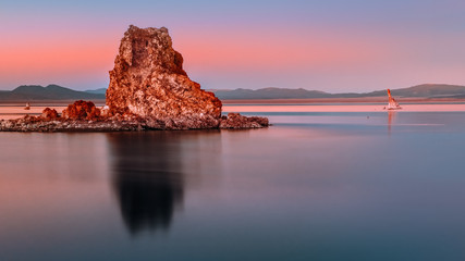 Smooth reflection of a big rock with mountains in the background