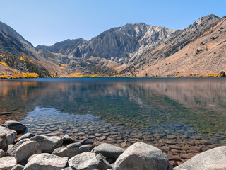 Autumn landscape with stones in front of the lake and mountains