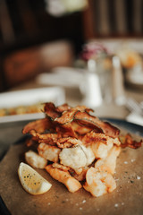 A close up shot of deep fried seafood platter with vegetables on a brown greaseproof paper. Concept of food, catering and restaurant.