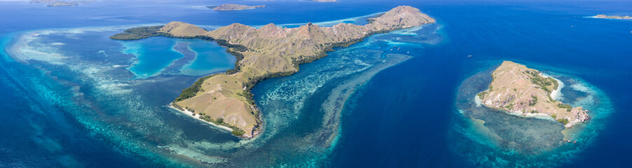 Seen from a bird's eye view, idyllic islands are surrounded by healthy coral reefs in Komodo National Park, Indonesia. This tropical area is known for its marine biodiversity as well as its dragons.