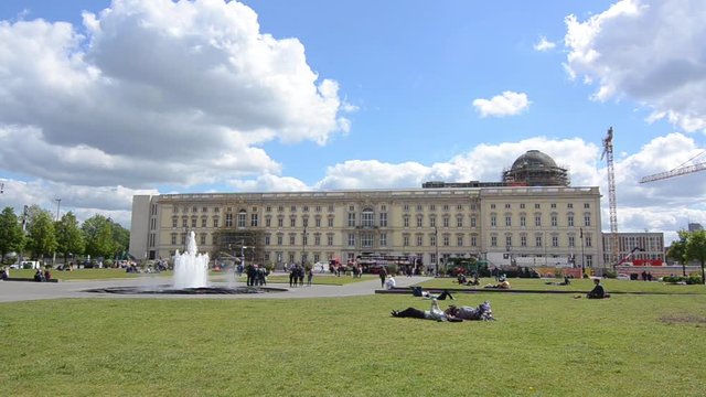 People are relaxing and laying on the grass at Lustgarten park on sunny spring day, Museum Island, Mitte district, Belin, Germany. People in front of the Altes Museum and Berlin Cathedral. Pleasure Ga