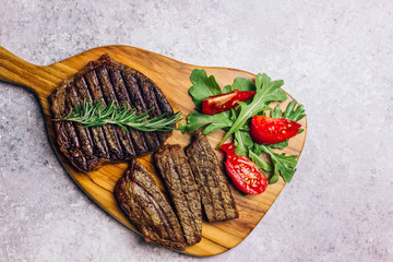 grilled beef steaks with spices on wooden cutting board