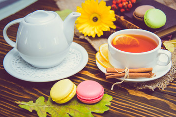 A cup of black tea with macaroons and lemon on the table.