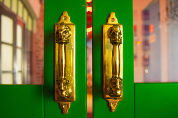 golden door handles on the green wooden door. Abstract background with space.