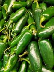 Detail of fresh green jalapeno peppers grouped on the shelf of a supermarket