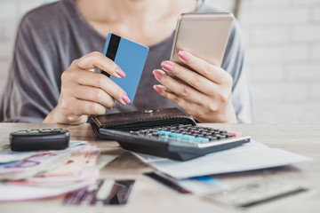 woman hand calculating  her expenses and debt from credit cards with smart phone 