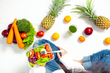 Top view of Young woman holding healthy vegetable salad and sitting with fresh fruit and Healthy diet, Concern Over Food Safety about Toxins in food. Antioxidant in meal, Clean eating food concept.