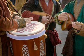 Street musicians in national costumes play folk instruments - a drum and a dombra during a holiday