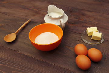Eggs, flour, sugar and butter for making dough on a rustic wooden table.