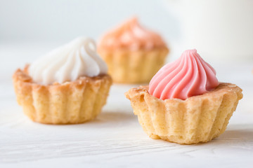Small cakes and with cream on a white table. Selective focus. 