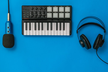Music mixer,microphone and headphones on blue background. The concept of workplace organization.
