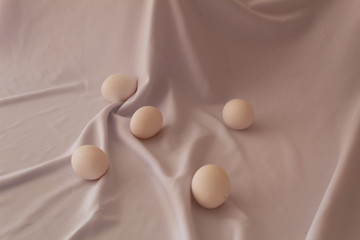A group of white chicken eggs on a white fabric background