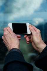 Old woman holding a smartphone to take pictures