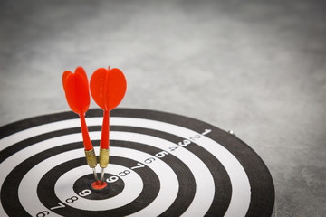 Red dart arrow hitting in the target center of dartboard on bullseye with sun light vintage style,...