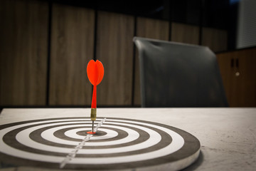 Red dart arrow hitting in the target center of dartboard on bullseye with sun light vintage style,...