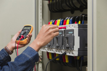 Electrician engineer work  tester measuring  voltage and current of power electric line in electical cabinet control.