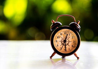 Alarm clock is located on the table with bokeh.
