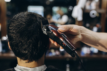 Hairdresser doing hair in the barber shop with clipper.