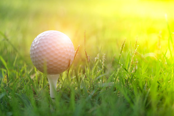 Golf ball on tee in beautiful golf course at sunset background.