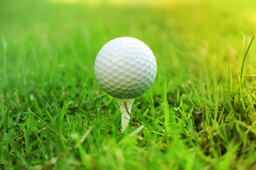 Golf ball on tee in beautiful golf course at sunset background.