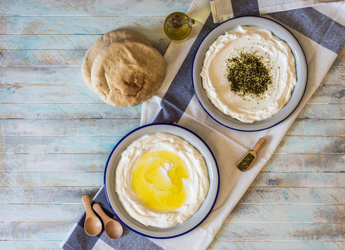 labneh labaneh middle eastern soft goat's milk cheese with olive oil, za'atar ,pita bread ,served at traditional concept over rustic turquoise wooden plate, flatlay,top view,copy space	