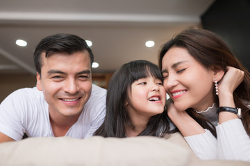 happy asian family spending time together on sofa in living room. family and home concept