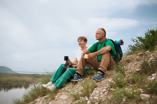 elderly couple with backpacks travels around mountains. Senior couple walking in nature