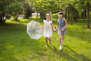 Fototapeta premium little girls with an umbrella playing out in the rain in the summer outdoors
