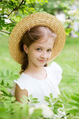  smiling little girl with hat in the blossoming garden